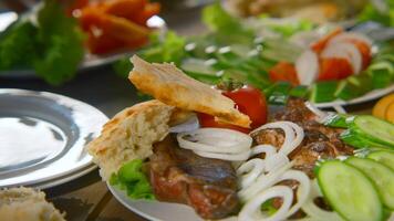Close-up of table with meat and vegetables in nature. Stock footage. Fresh vegetables and juicy meat on table on sunny summer day. Table with vegetables and meat in nature in summer video