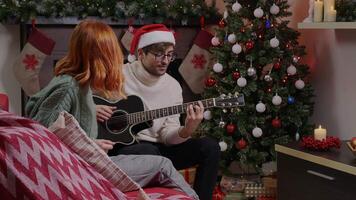 lado ver de un Pareja jugando el guitarra acuerdo el ritmo de un Navidad canción. video