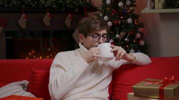 A single man sitting in front TV with cup of tea and watching Christmas TV show. video