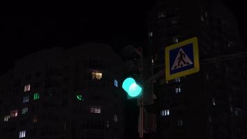 Switching traffic light at night intersection in city. Concept. Changing traffic lights for cars in night city. Glowing traffic light changes lights at intersection of night city video