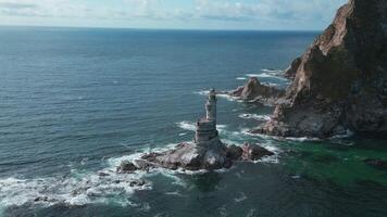 Top view of rocky cape landscape and lighthouse in sea. Clip. Fabulous landscape of rocky cape of island with abandoned lighthouse. Seascape with rocky cape and lighthouse on sunny day video