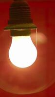 An illuminated light bulb hangs elegantly against a dark background, creating visual contrast. Stock Clip video