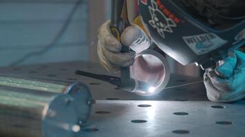 Engineer in a protective mask makes welding of metal pipe. Creative. Face of welder is close to sparks. video