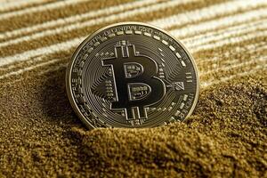 A Bitcoin coin partially buried in sand, symbolizing the cryptocurrency's potential and hidden value. photo