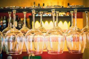 A bar with a rack of wine glasses photo