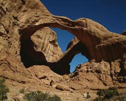 Majestic Natural Arch Overlooking a Serene Landscape and Bedrock Formation photo