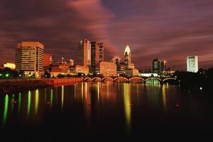 Serene Dusk Reflection of Skyscrapers on a Tranquil Lake Under a Cloudy Sky photo