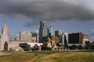 Urban Skyline with Skyscrapers and Greenery Against a Cloudy Sky photo