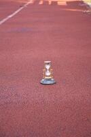 A small hourglass on the ground in a running track photo