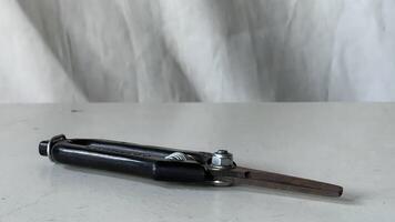 Metal compass resting on a white table with a textured background photo