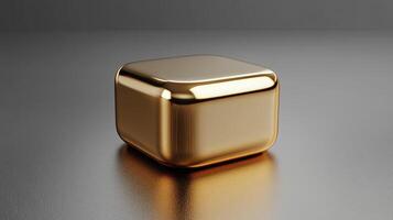 Shiny gold cube resting on a gray surface reflecting light photo