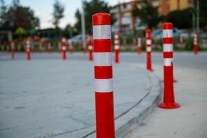 Orange traffic cone, parking is prohibited. Plastic red barrier. Row of red and white traffic barrier pole on road. A barrier made of plastic columns with reflective pigment on an asphalt road. photo
