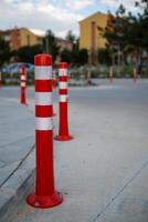 Orange traffic cone, parking is prohibited. Plastic red barrier. Row of red and white traffic barrier pole on road. A barrier made of plastic columns with reflective pigment on an asphalt road. photo