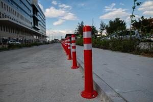 Orange traffic cone, parking is prohibited. Plastic red barrier. Row of red and white traffic barrier pole on road. A barrier made of plastic columns with reflective pigment on an asphalt road. photo