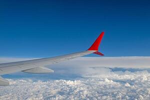 Blue sky, white clouds and aircraft wing from the aircraft window on a beautiful sunny day. photo