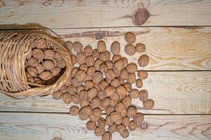 Poured walnuts in a wicker basket on a wooden table. View from above. photo