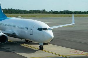Passenger aircraft entering the platform at an airport. Woodland and sky in the background. photo