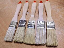 Five Wooden Paintbrushes on Wooden Surface photo