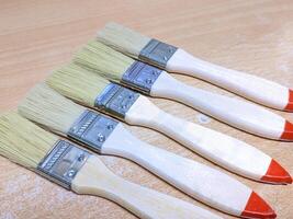 Five Wooden Paintbrushes on Wooden Surface photo