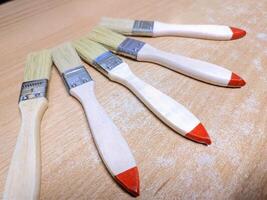 Five Wooden Paintbrushes on Wooden Surface photo