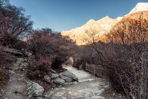 Trail in autumn valley with sunrise on mountain range photo