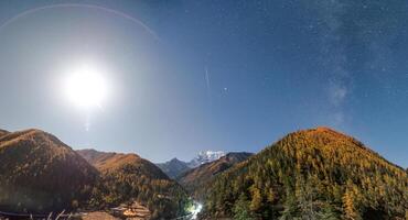 Panorama of mountain with pine forest with shooting star, milky way and the moon in national park photo