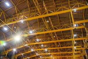 Yellow metal structure on roof with lamp lighting in storehouse photo