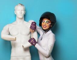 Model with bright creative make up with helmet and male dummy photo