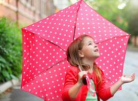 Little girl with polka dots umbrella under the rain photo