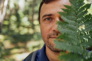 Close-up portrait of young happy man with fern in nature. photo