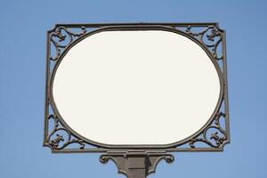 a white sign with a circular frame against a blue sky photo
