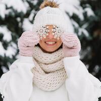 Happy woman in white winter clothes holding a beautiful snowflake in a park. Happy winter concept photo
