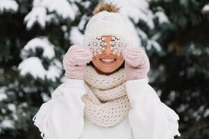 Happy woman in white winter clothes holding a beautiful snowflake in a park. Happy winter concept photo
