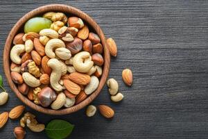 Colorful fruit and nut mix served in glass bowl with other nuts on the table photo