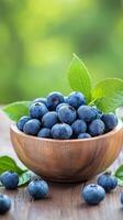 Freshly picked blueberries in a wooden bowl surrounded by green leaves photo