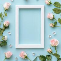 Floral decoration with white frame and pastel roses on soft blue background photo