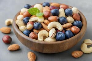 Colorful fruit and nut mix served in glass bowl with other nuts on the table photo