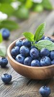 Freshly picked blueberries in a wooden bowl surrounded by green leaves photo