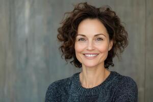 Smiling woman with curly hair poses against a wooden backdrop in natural light photo