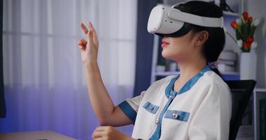 Handheld zoom in shot, Freelance Asian woman sitting at desk using laptop and wearing virtual reality glasses to explain work during online meeting in home office. Working from home. video