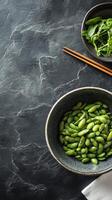 Fresh edamame in bowl with chopsticks on dark surface ready for a nutritious snack photo