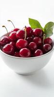 Fresh cherries in a clear glass bowl on a light background photo