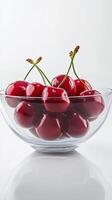 Fresh cherries in a clear glass bowl on a light background photo