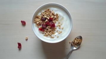 Delicious yogurt bowl topped with granola and cranberries served in a white dish photo