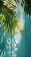 Palm leaves casting shadows on a blue wooden background in bright daylight photo