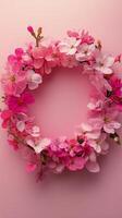 Beautiful floral wreath crafted from pink cherry blossoms against a soft pink background photo