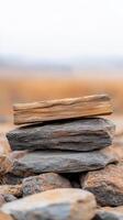 Stacked stones and wood in a natural setting near a blurred landscape during daytime photo