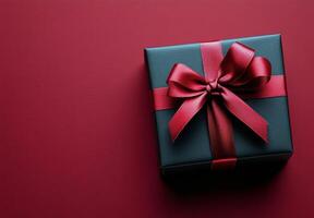 Elegant black gift box with a red ribbon against a deep red background photo