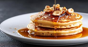 Stack of fluffy pancakes drizzled with syrup and topped with nuts on a rustic table photo
