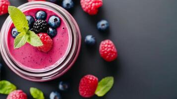 Berry smoothie in a glass with fresh mint and fruits on a dark background photo